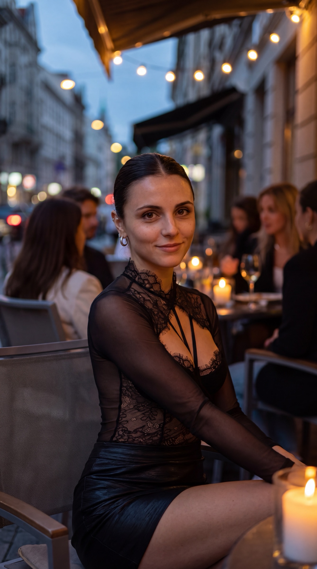 Soaira at an outdoor café at night, lace top, string lights behind her